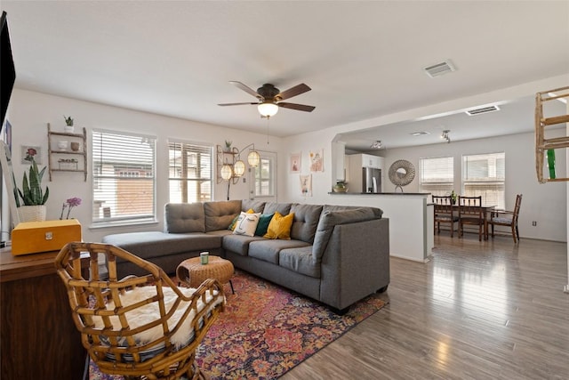 living room with ceiling fan, wood finished floors, and visible vents