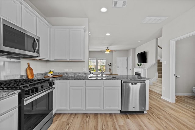 kitchen featuring visible vents, appliances with stainless steel finishes, white cabinets, and dark stone counters