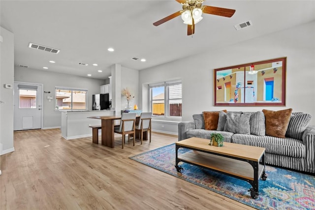 living area featuring light wood-type flooring, visible vents, and baseboards