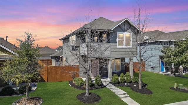 view of front of property with a balcony, fence, and a front lawn