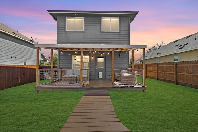 back of house at dusk featuring a lawn and a fenced backyard