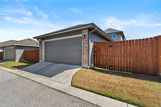 view of front of house with driveway, brick siding, and fence