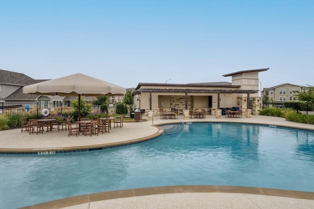 pool with a patio area and fence