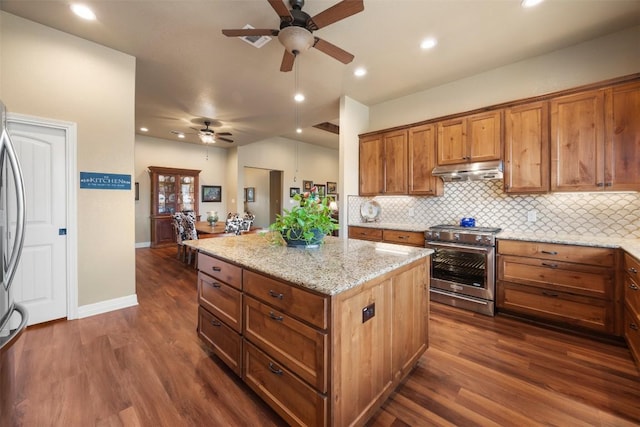 kitchen featuring dark wood finished floors, brown cabinetry, a kitchen island, high end range, and under cabinet range hood