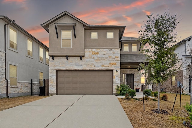 view of front of property with driveway, stone siding, a garage, and stucco siding