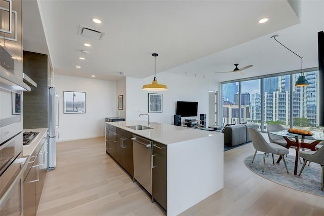 kitchen featuring light wood-style flooring, stainless steel appliances, a sink, visible vents, and modern cabinets