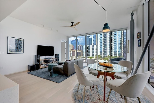 dining area with a wall of windows, a ceiling fan, and wood finished floors