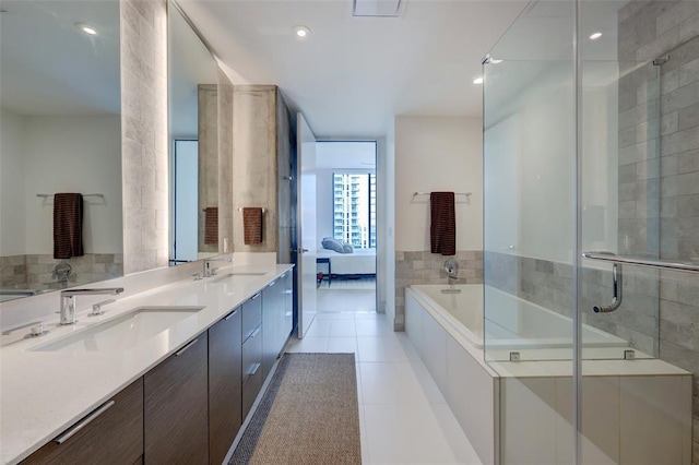 bathroom with double vanity, tile patterned flooring, a sink, and a bath