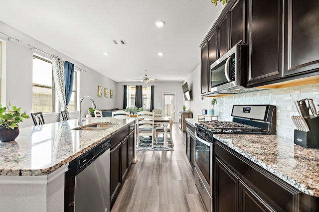 kitchen featuring tasteful backsplash, visible vents, open floor plan, stainless steel appliances, and a sink