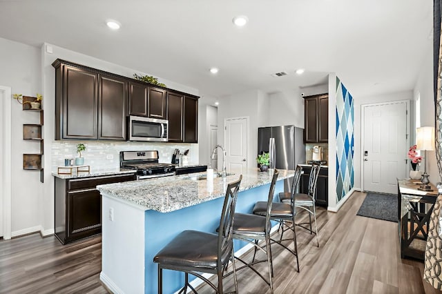 kitchen with light wood-type flooring, tasteful backsplash, stainless steel appliances, and dark brown cabinets