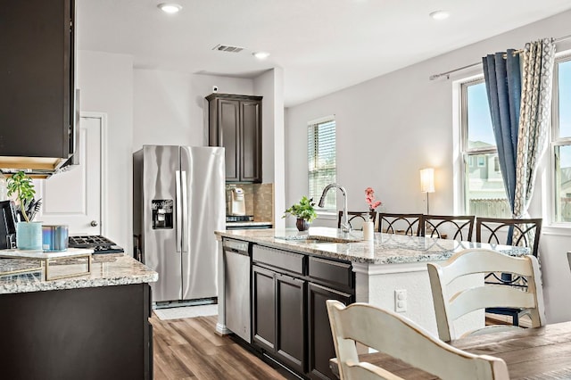 kitchen with light stone counters, visible vents, stainless steel appliances, and a sink