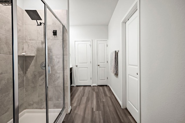 full bathroom with a shower stall, baseboards, and wood finished floors