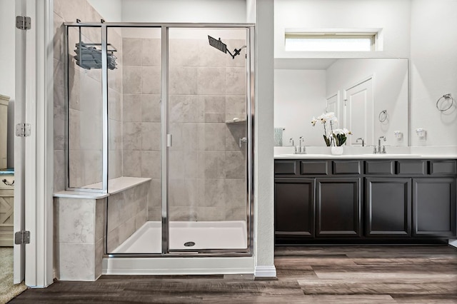 bathroom featuring a stall shower, double vanity, and wood finished floors