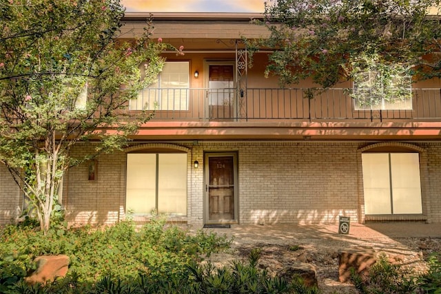 exterior space featuring brick siding, board and batten siding, and a balcony