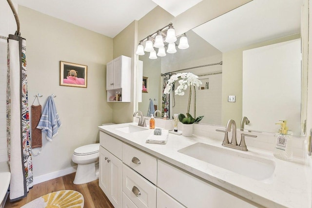 full bathroom with wood finished floors, a shower with shower curtain, a sink, and toilet