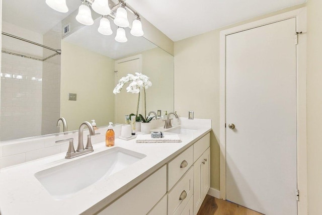 bathroom featuring wood finished floors, visible vents, a sink, and double vanity