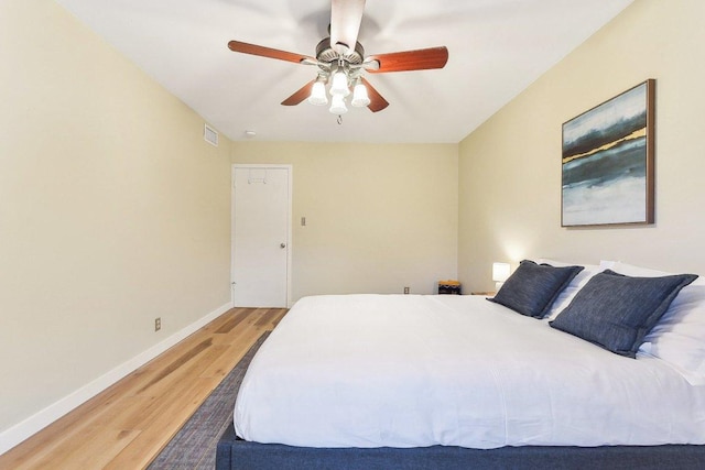 bedroom featuring light wood-style floors, visible vents, baseboards, and a ceiling fan