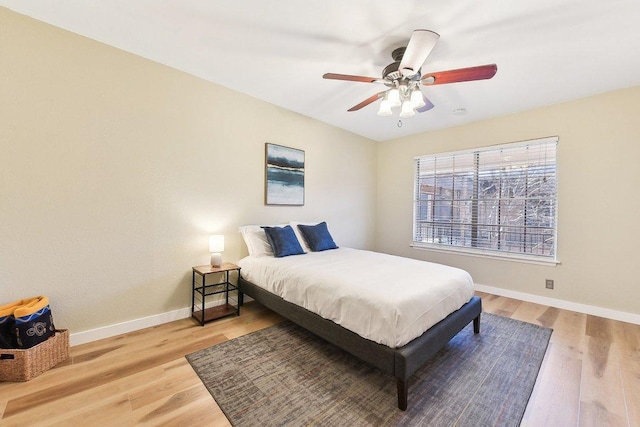 bedroom featuring a ceiling fan, baseboards, and wood finished floors