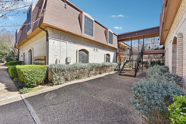 7801 Shoal Creek Blvd Unit 224, Austin, TX 78757 - view of side of property with a wooden deck, a shingled roof, stairs, brick siding, and mansard roof