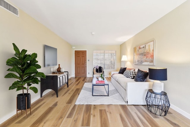 living room with baseboards, visible vents, and light wood-style floors