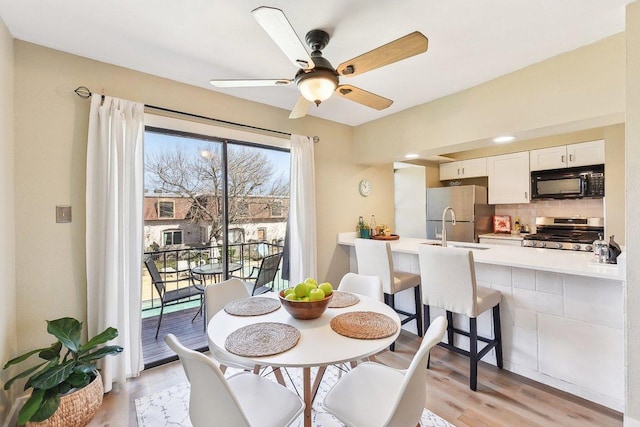 dining area with light wood-style floors and ceiling fan