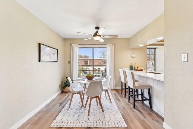 dining area with a ceiling fan, baseboards, and light wood finished floors