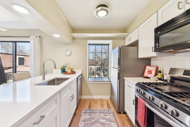 kitchen with white cabinets, appliances with stainless steel finishes, light countertops, and a sink