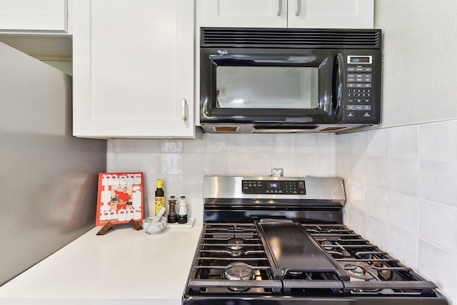 kitchen featuring black microwave, white cabinets, light countertops, backsplash, and stainless steel range with gas stovetop