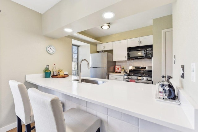 7801 Shoal Creek Blvd Unit 224, Austin, TX 78757 - kitchen featuring a sink, a breakfast bar, a peninsula, white cabinets, and appliances with stainless steel finishes