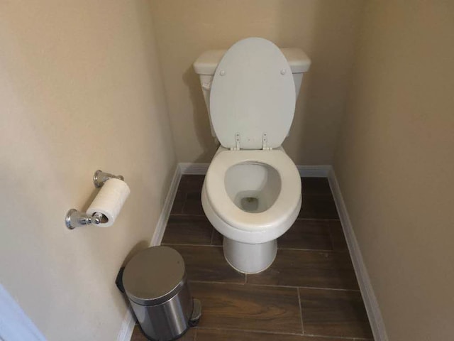 bathroom with wood finished floors, toilet, and baseboards