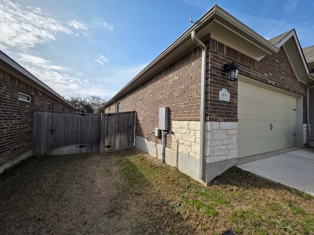 view of side of property featuring a garage, stone siding, brick siding, and fence