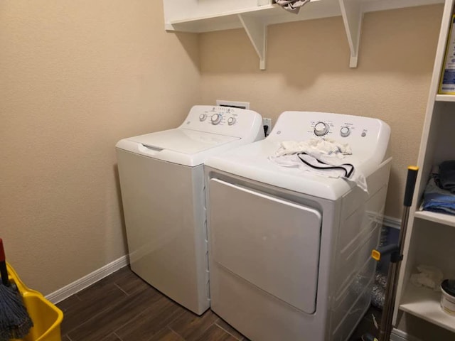 washroom featuring laundry area, washer and clothes dryer, dark wood finished floors, and baseboards