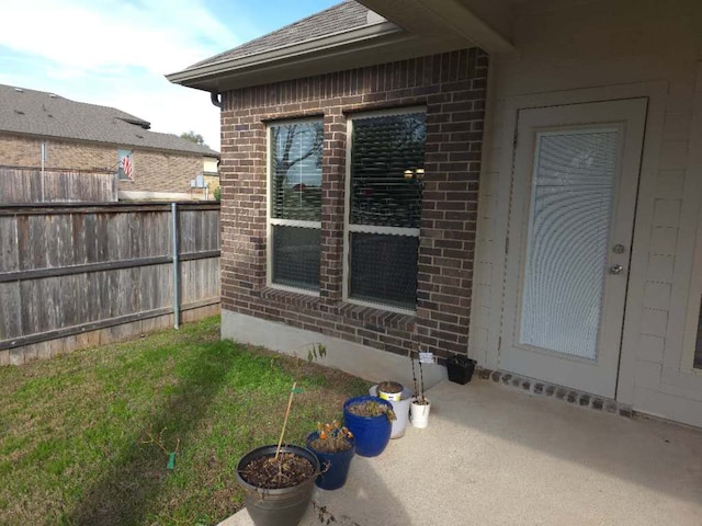 view of side of property with a shingled roof, brick siding, and fence