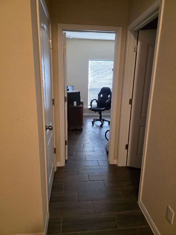 corridor featuring wood tiled floor and baseboards