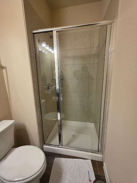 bathroom with a shower stall, toilet, and baseboards