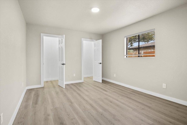 unfurnished bedroom featuring a textured ceiling, wood finished floors, and baseboards