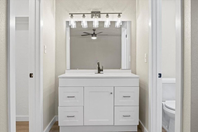 bathroom featuring toilet, baseboards, wood finished floors, and vanity