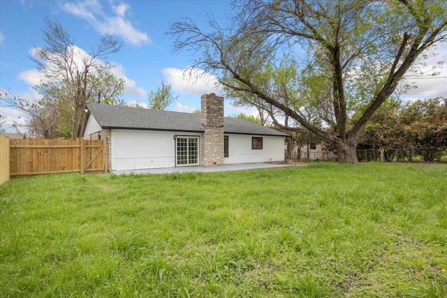 rear view of property with a fenced backyard, a yard, a chimney, and a patio