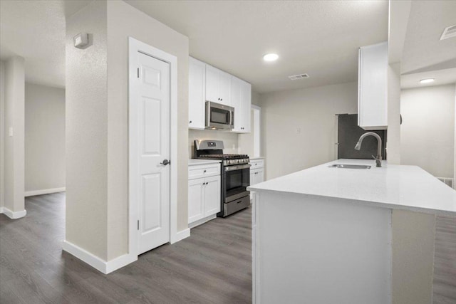 kitchen with dark wood-type flooring, a sink, visible vents, white cabinets, and appliances with stainless steel finishes