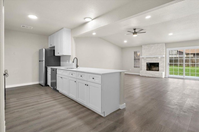 kitchen with visible vents, white cabinets, appliances with stainless steel finishes, a fireplace, and a sink