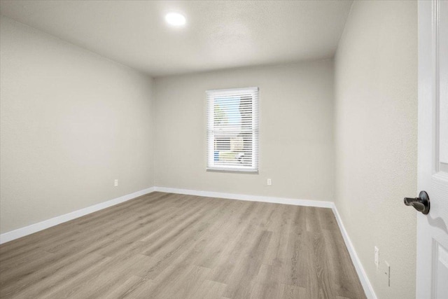 empty room featuring light wood-type flooring and baseboards