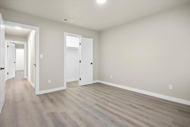 unfurnished bedroom with baseboards, a closet, visible vents, and wood finished floors