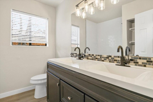 bathroom with backsplash, a sink, toilet, and a healthy amount of sunlight