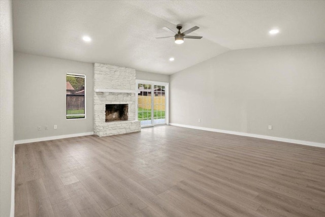 unfurnished living room with lofted ceiling, plenty of natural light, a fireplace, and wood finished floors