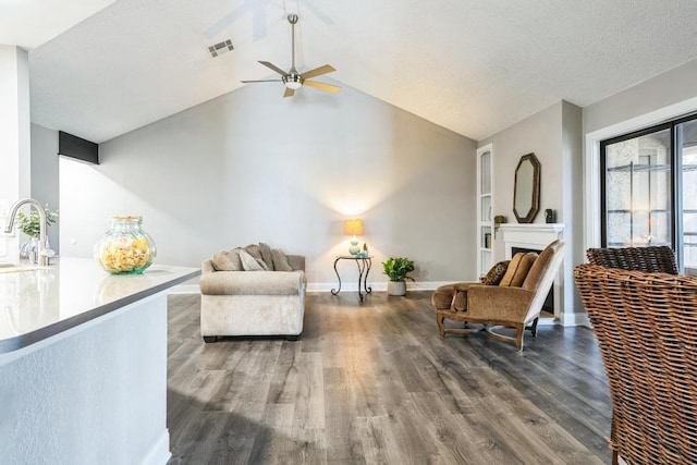 living area featuring lofted ceiling, a fireplace, baseboards, and wood finished floors