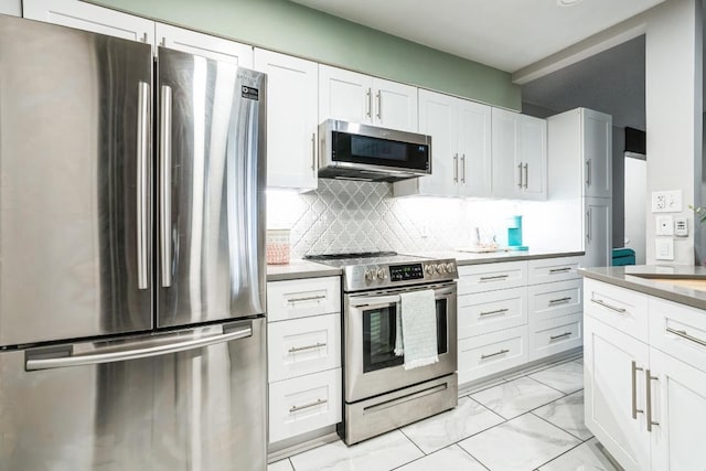 kitchen with marble finish floor, white cabinetry, appliances with stainless steel finishes, and backsplash