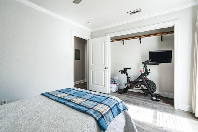 bedroom featuring crown molding, visible vents, wood finished floors, electric panel, and baseboards