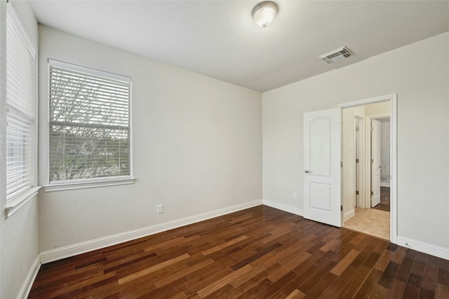 unfurnished bedroom featuring visible vents, baseboards, and wood finished floors