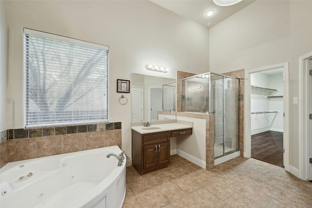 full bath featuring a walk in closet, a stall shower, vanity, tile patterned flooring, and a tub with jets