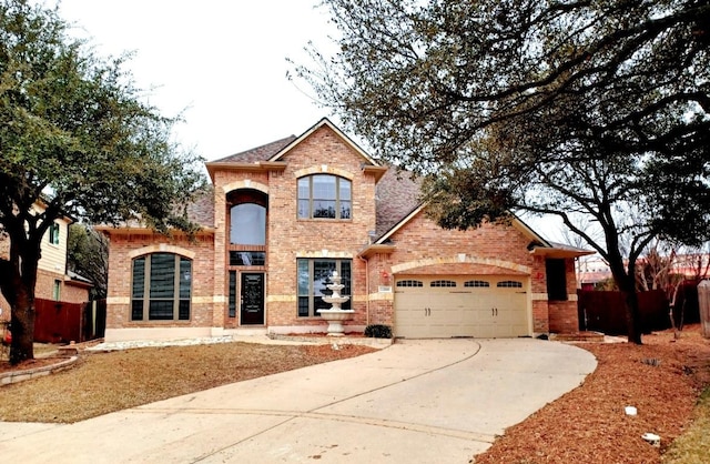 traditional-style house featuring a garage, concrete driveway, brick siding, and fence